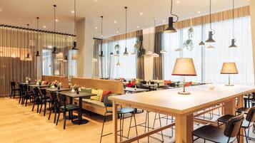 A modern restaurant with wooden tables, black chairs, and a central bar area.