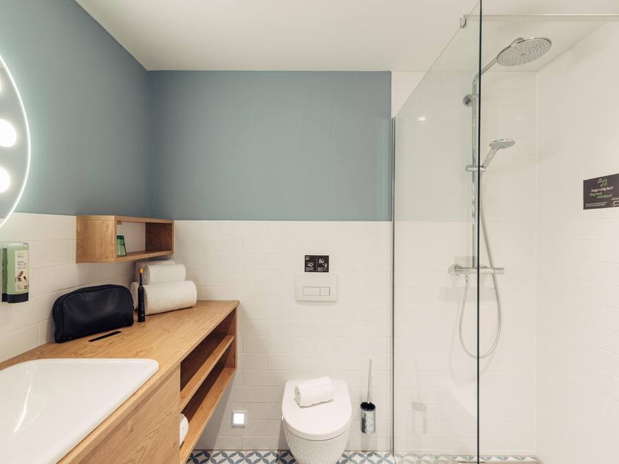 Un baño moderno con tocador, cabina de ducha de vidrio y espejo con iluminación.