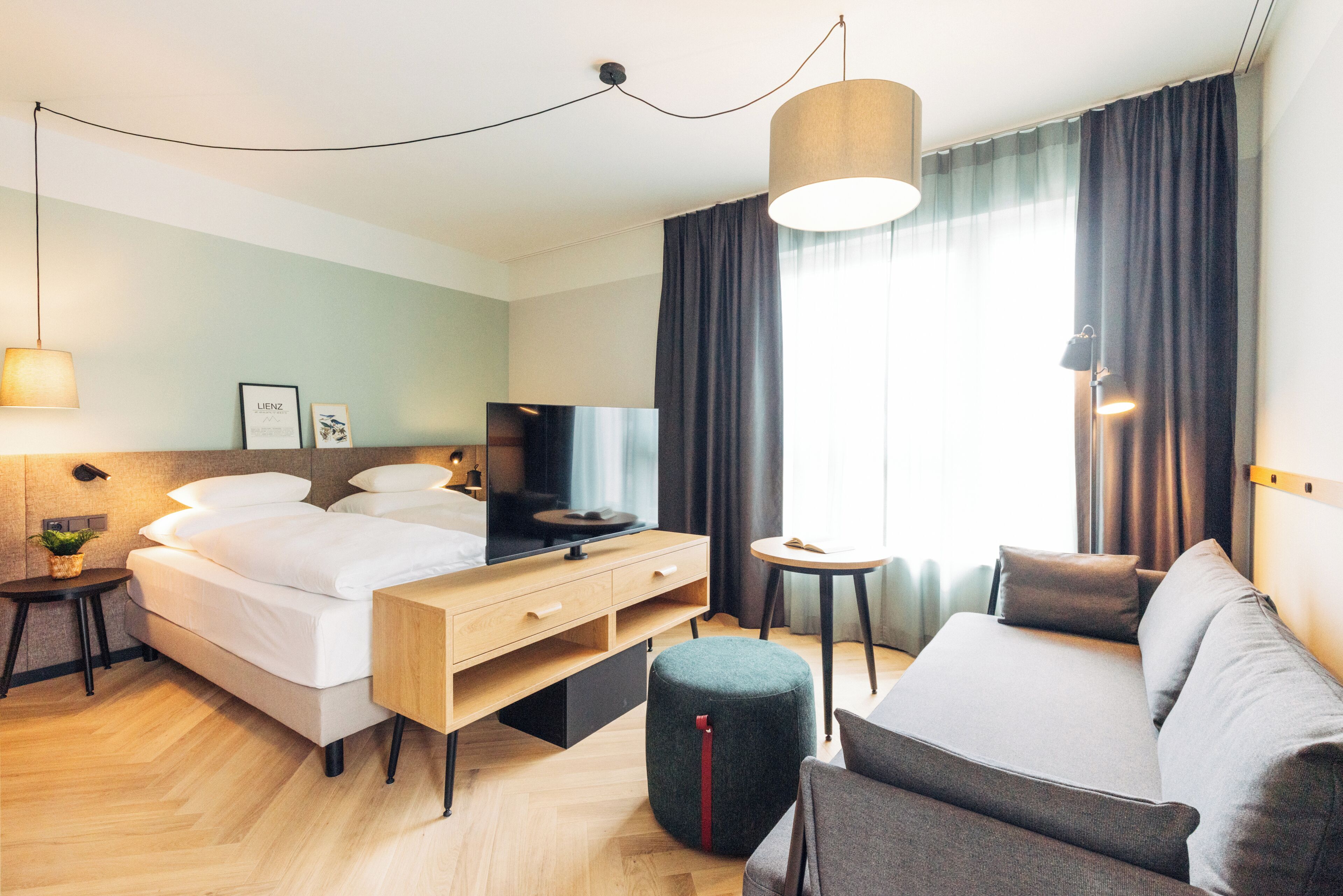 Une chambre d’hôtel moderne équipée d’un lit, d’un canapé, d’une télévision et d’une petite table.