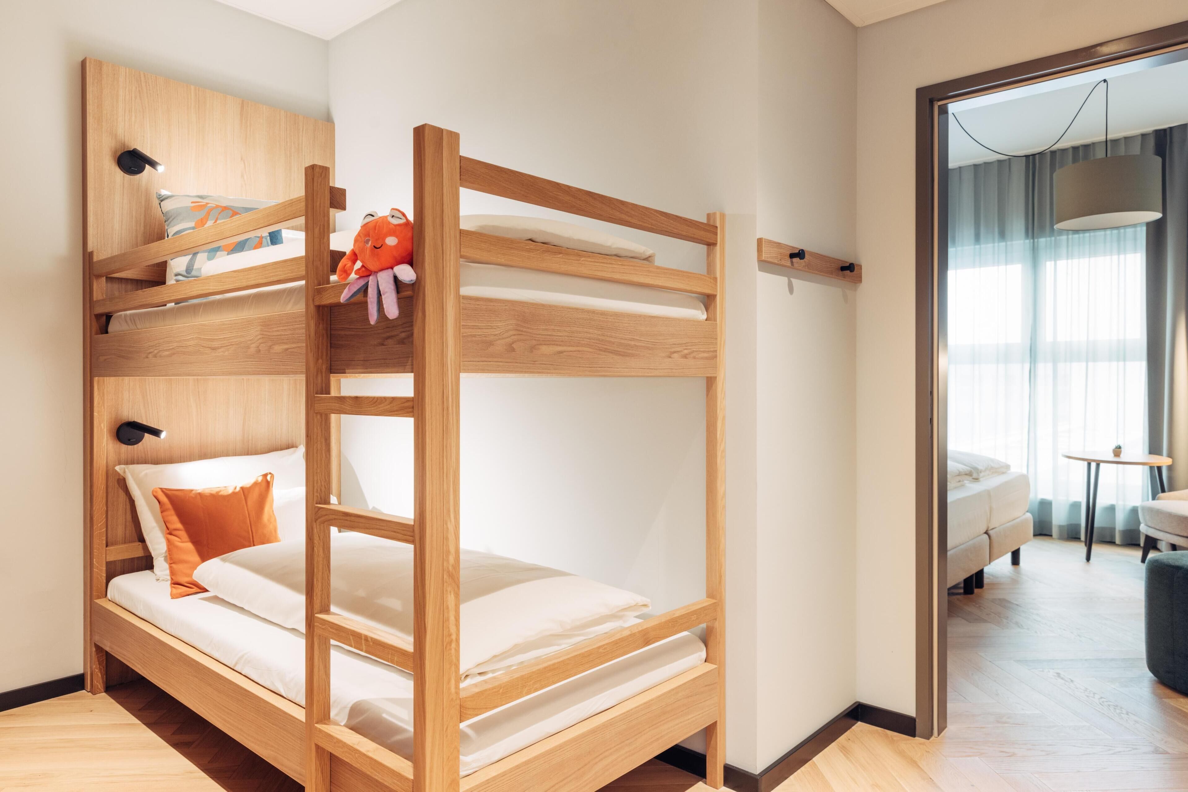 A bunk bed with a wooden frame, white bedding, and a plush toy on the top bunk.