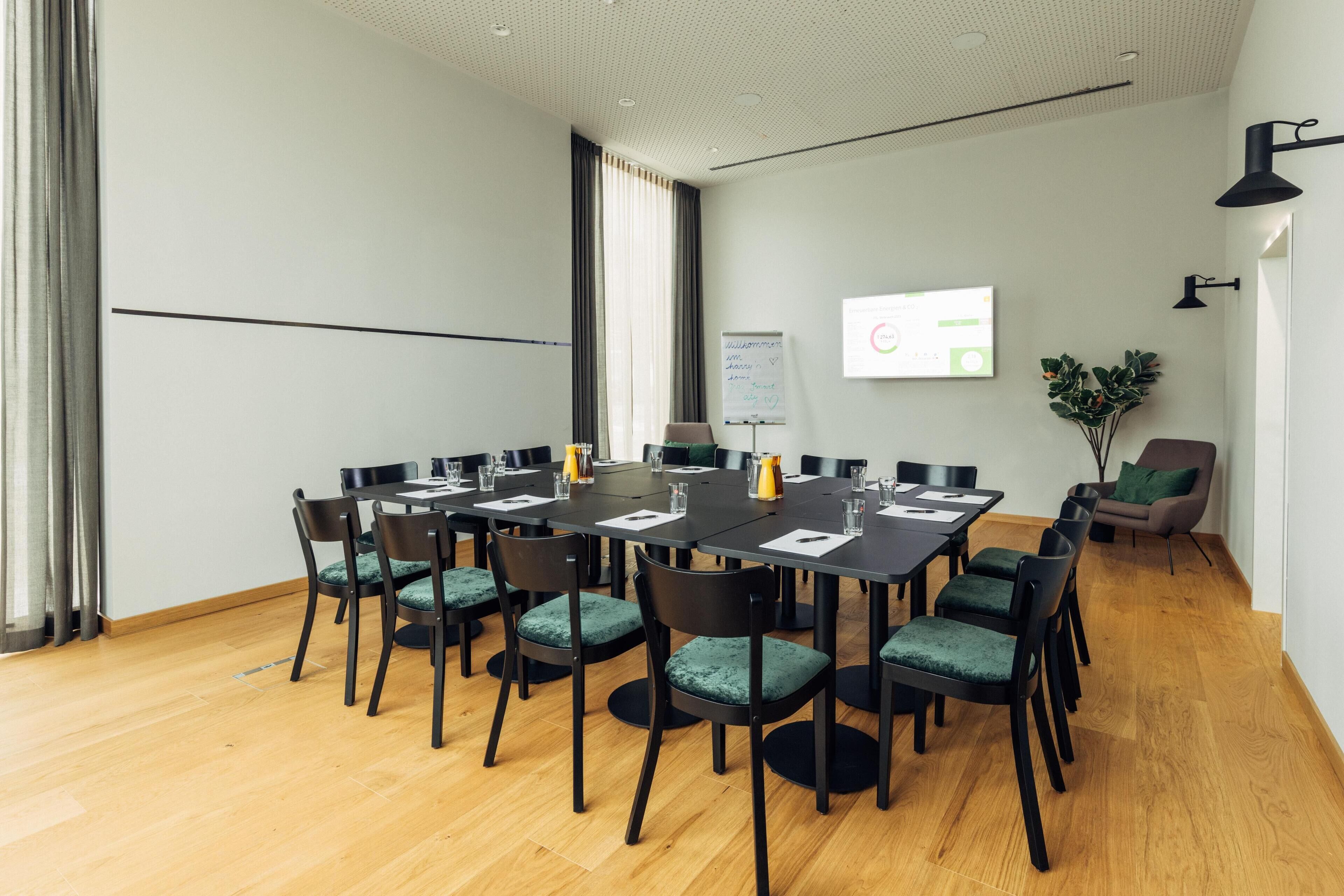 A conference room with a large table, chairs, a projector screen, and a whiteboard.