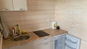 Angolo cottura compatto con lavandino, bollitore e piccolo frigorifero.