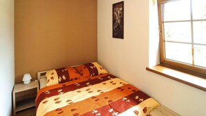 A bedroom with a bed, a nightstand, a window, and a painting on the wall. - Apartment in a Fantastic Location Just 20 m From Lake Boruja in Rekowo (Bytow)