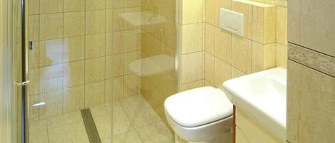 A bathroom with a glass-enclosed shower, a white toilet, and a sink with a mirror above it.