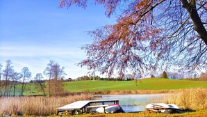 A lakeside picnic area with benches and tables, surrounded by trees and a grassy field. - Apartment in a Fantastic Location Just 20 m From Lake Boruja in Rekowo (Bytow)