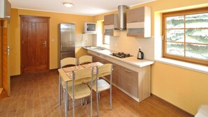 A compact kitchen with a built-in stove, a refrigerator, and a window with a view of trees. - Apartment in a Fantastic Location Just 20 m From Lake Boruja in Rekowo (Bytow)