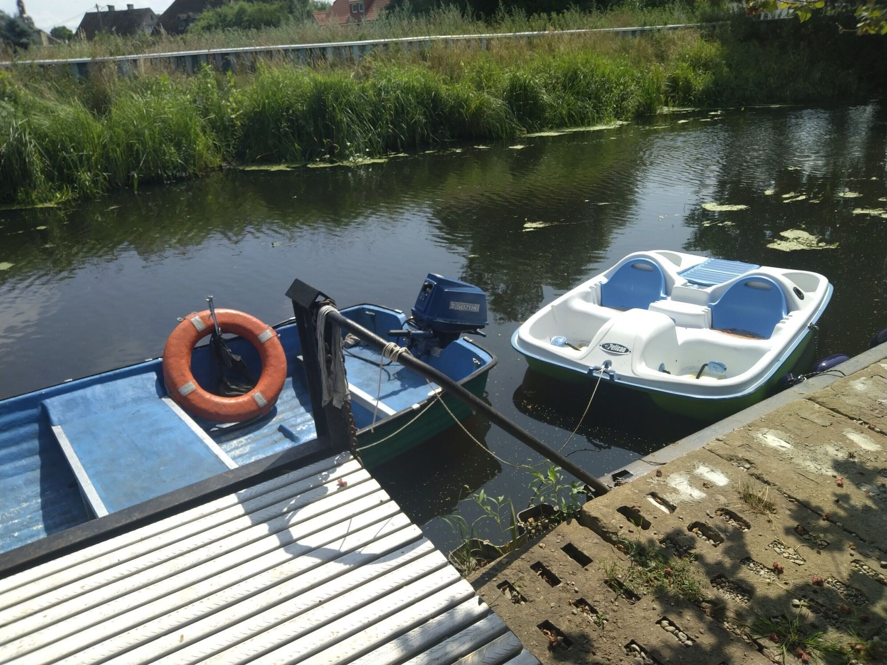A small boat docked at a pier with a life preserver attached.
