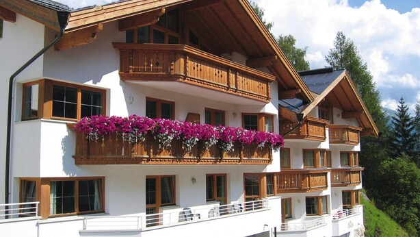 Ein mehrstöckiges Hotel mit hölzernen Balkonen und Blumenkästen.