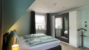 Ein modernes Schlafzimmer mit Bett, Nachttisch, Lampe, Kleiderschrank und Spiegel.