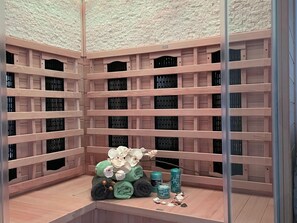 A spa room with wooden shelves, a small seating area, and a decorative arrangement including towels, candles, and seashells. - Holiday Home in Walkenried With Sauna (Walkenried)