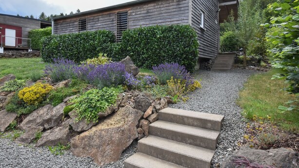 Une maison moderne avec un chemin de pierre menant à une terrasse en bois.