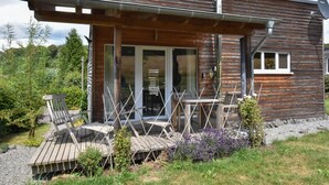 Une cabane moderne en bois dotée d’un patio couvert, de meubles d’extérieur et d’une antenne parabolique.
