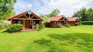 A row of wooden cabins with pitched roofs, satellite dishes, and a well-maintained lawn. - Holiday Homes With Terraces, Large Garden (Ustronie Morskie)