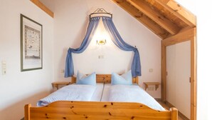A bedroom with a wooden bed, a canopy, a nightstand, and a wall-mounted light fixture.