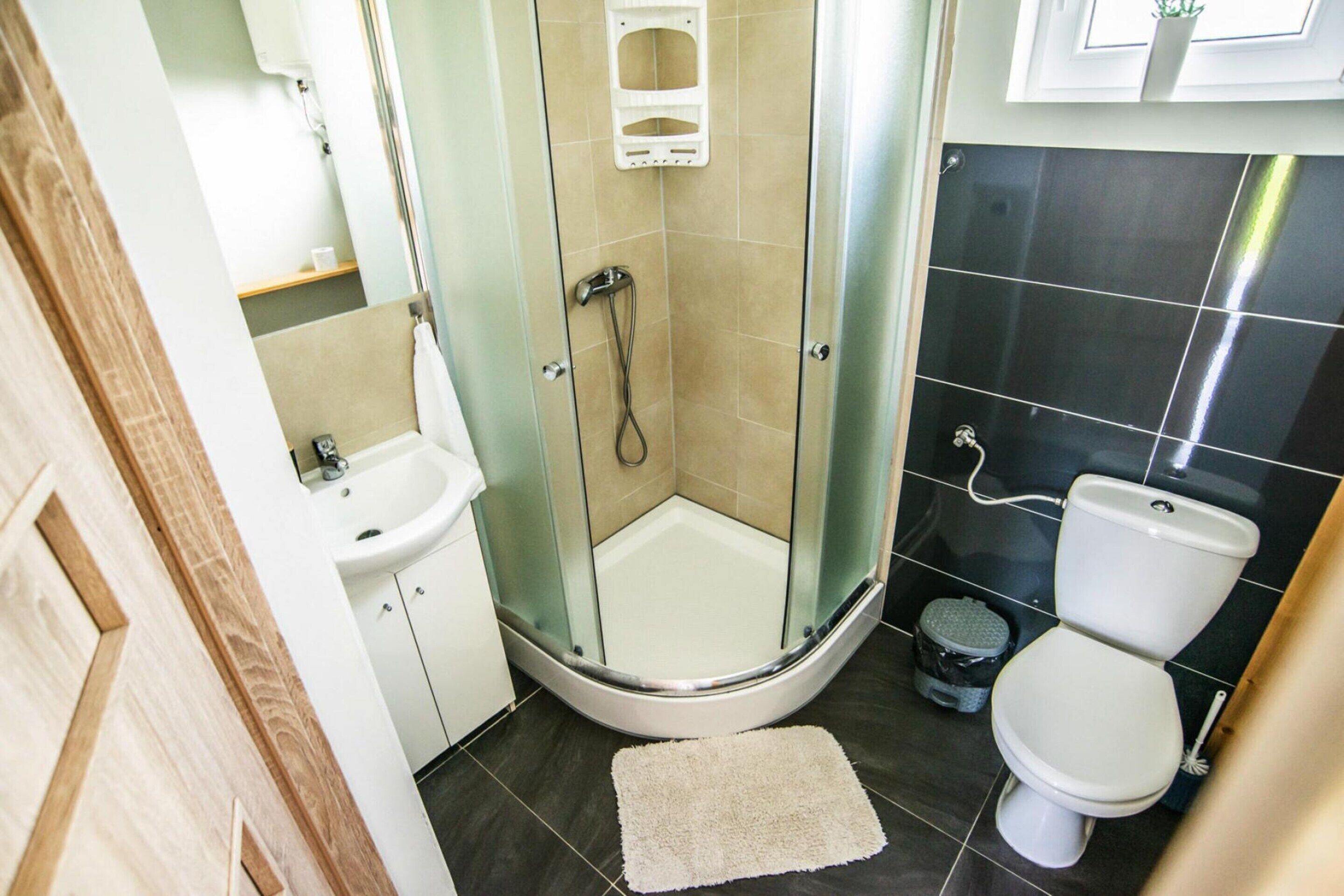 A bathroom with a glass-enclosed shower, a toilet, and a sink.