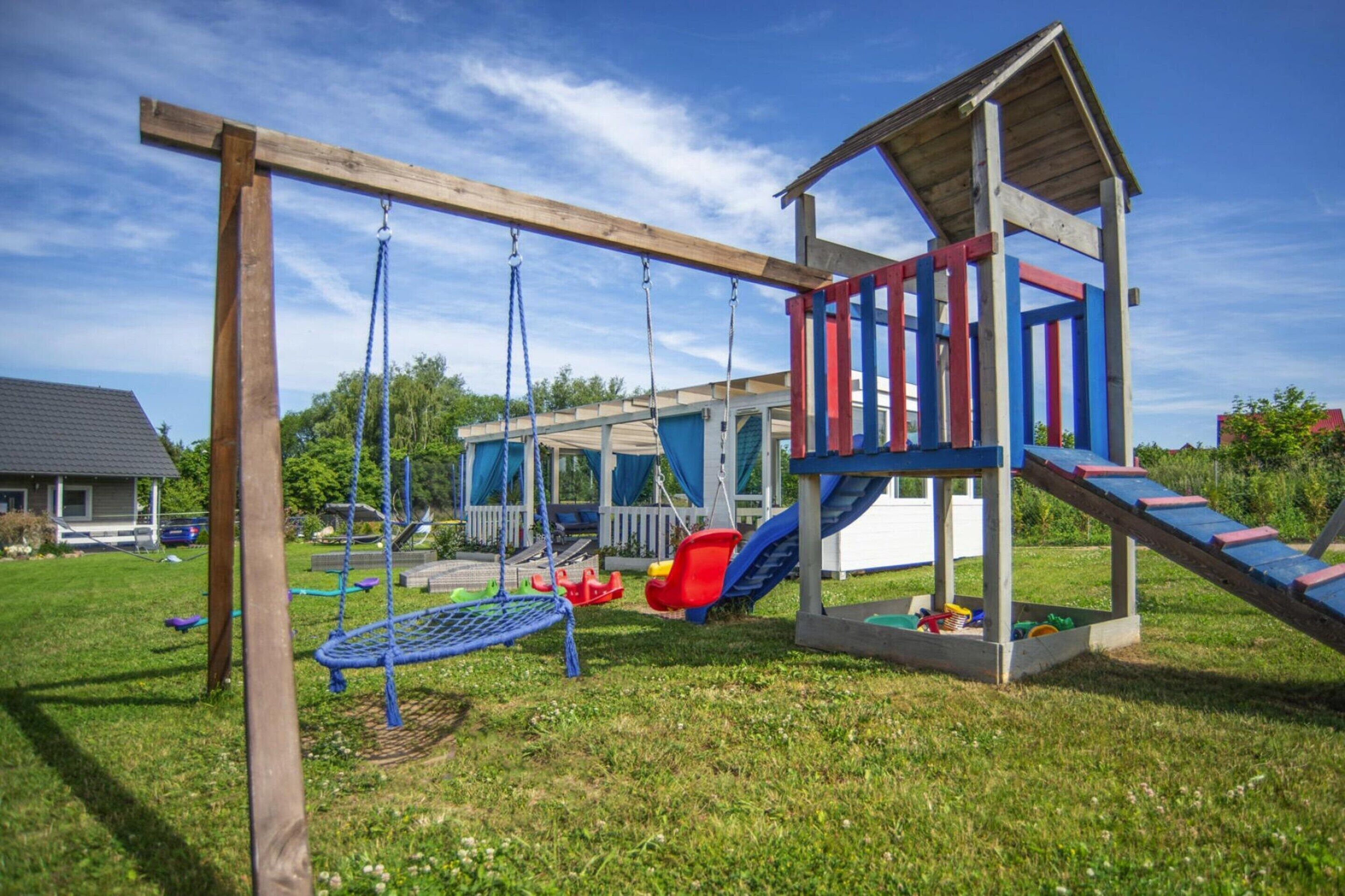 Une aire de jeux avec des balançoires, un toboggan et une structure d’escalade.