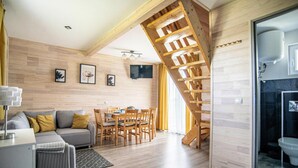 Un salon moderne comprenant un canapé, une table à manger et des chaises, un escalier, ainsi qu’une salle de bain avec douche et toilettes.