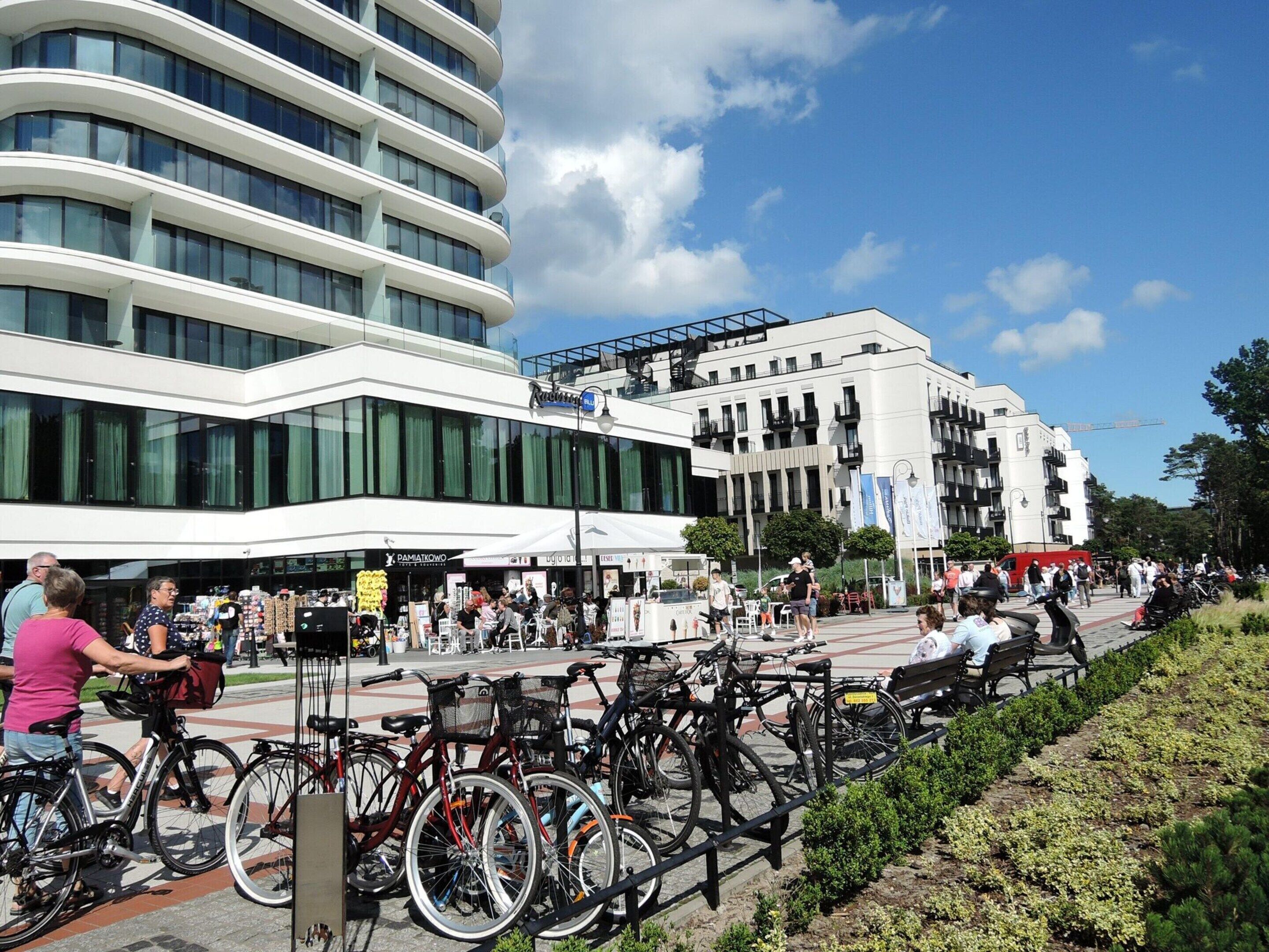 A modern building with a curved facade, outdoor seating, and bicycles parked in front.