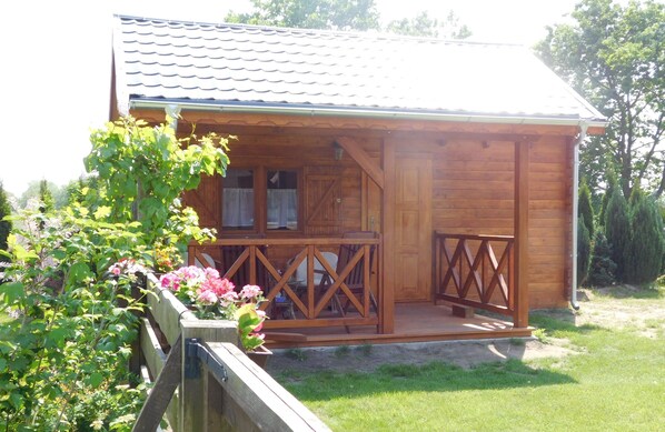 A wooden cabin with a porch, a small window, and a door. - Wooden House in Karsibor Near Baltic Beaches (Swinoujscie)