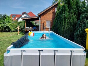 An inflatable pool with a person swimming and another standing by.