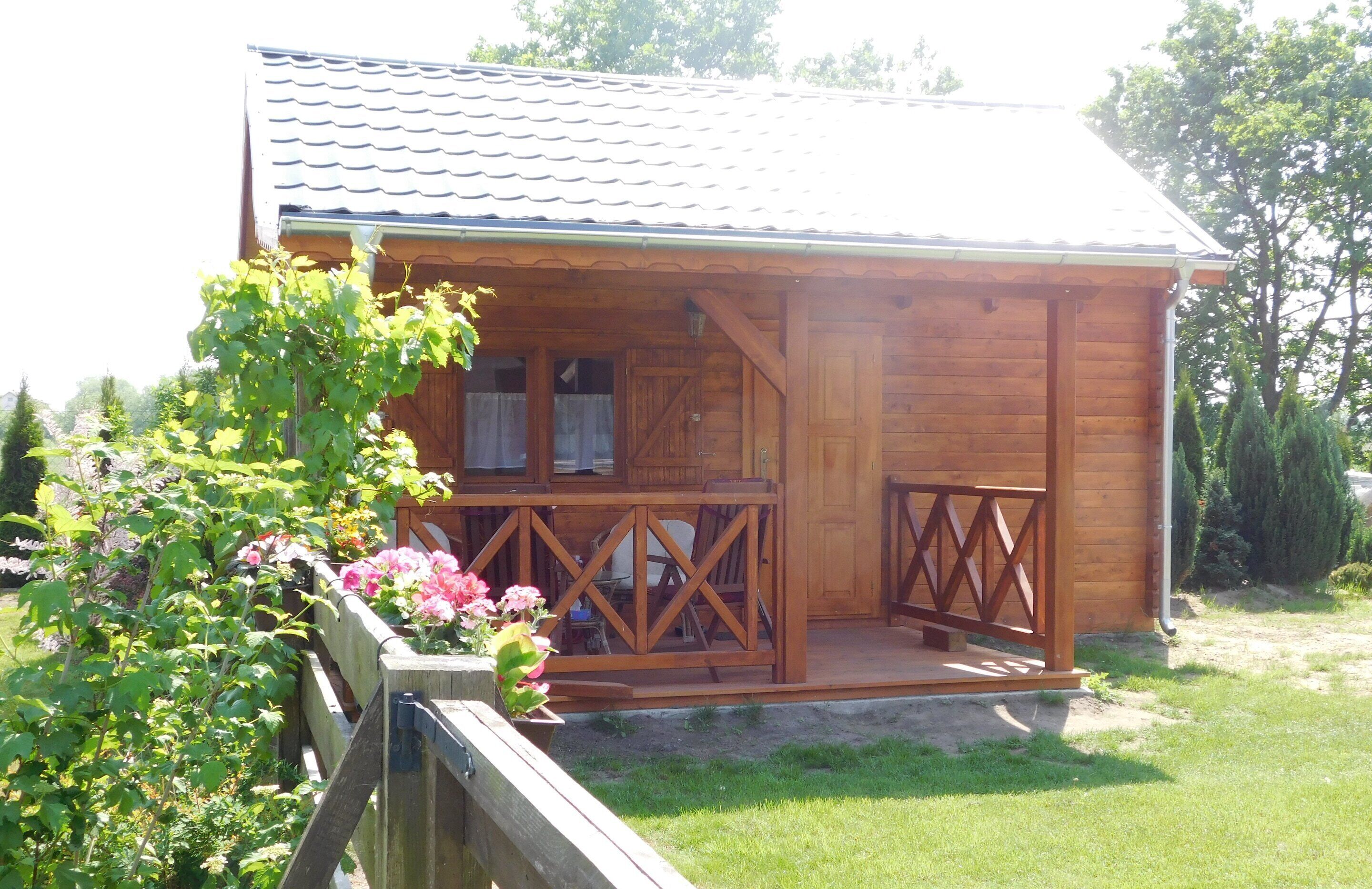 A wooden cabin with a porch, a window, and a door.