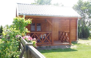 A wooden cabin with a porch, a window, and a door.