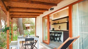 An outdoor patio with a wooden deck, a dining table with chairs, and a seating area with a chair.