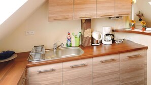 A modern kitchen with wooden cabinets, a stainless steel sink, and a coffee maker. - Apartment in Swinoujscie Near Baltic Beach (Swinoujscie)