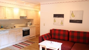A compact living space with a kitchenette, a red plaid sofa, and a small white table. - Apartment in Krimml With Balcony (Krimml)