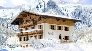 A two-story wooden building with balconies, surrounded by snow-covered mountains. - Apartment in Krimml With Balcony (Krimml)