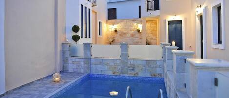A pool area with stone walls, a small pool, and a railing.