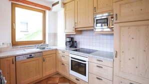 Een keuken met houten kastjes, een ingebouwde magnetron, een koffiezetapparaat en een vaatwasser.