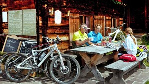 Een houten terras met een stenen vloer, fietsen en een menubord.