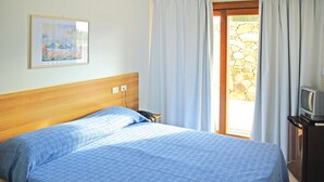 A bedroom with a bed, a painting on the wall, a television on a stand, and a stone wall outside the door. - Apartment in Sardinia Near Surfing Paradise (Palau)