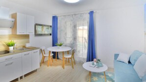 A modern, well-lit living room with a dining area, a sofa, and a kitchen with white cabinets and a sink. - Cozy Holiday Studio, Close to the Beach (Kołobrzeg)