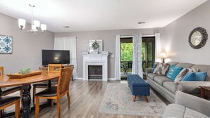 A living room with a fireplace, a dining table with chairs, a sofa, and a TV. - Serenitee Pointe; Resort Access Indoor/Outdoor Pools & Hot Tub! (Branson)