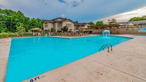 A swimming pool with a 4 FT depth marker, surrounded by a building with a covered patio area. - Serenitee Pointe; Resort Access Indoor/Outdoor Pools & Hot Tub! (Branson)