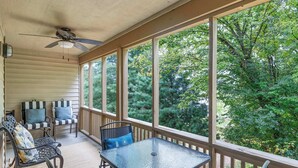 A covered porch with a table and chairs, large windows, and a ceiling fan. - Serenitee Pointe; Resort Access Indoor/Outdoor Pools & Hot Tub! (Branson)