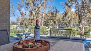 A table with a bottle of wine, two glasses, and a wooden board with various snacks. - Marina Views (Moama)