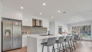 A modern kitchen with a central island, stainless steel appliances, and a large window overlooking a garden. - Marina Views (Moama)