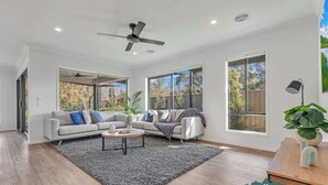 A spacious living room with a large window, a ceiling fan, and a modern sofa set. - Marina Views (Moama)