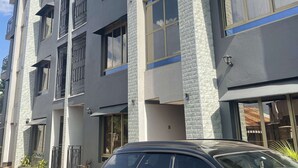 A multi-story building with a modern architectural design, featuring large windows and a car parked in front. - Luxury One Bedroom Apartment Kampala Uganda. (Kampala)