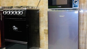 A kitchen with a black stove, a silver refrigerator, and a microwave on top of the fridge. - Luxury One Bedroom Apartment Kampala Uganda. (Kampala)