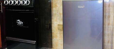 A kitchen with a black stove, a silver refrigerator, and a microwave on top of the fridge.