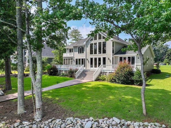 A two-story house with a front porch, a staircase leading to the entrance, and a well-maintained lawn.
