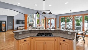 Una cocina con encimera de granito, armarios de madera, estufa a gas y una lámpara colgante.