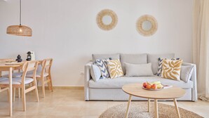 Una sala moderna con un sofá, espejos redondos, una mesa de comedor con sillas y una mesa de centro con fruta.