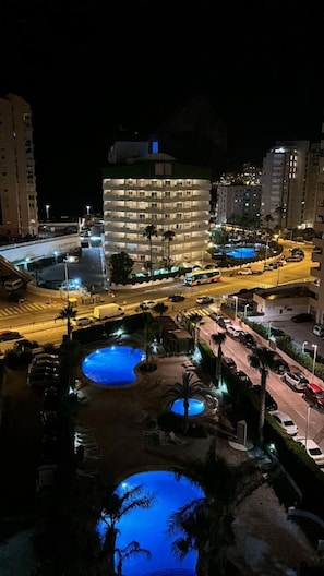 A multi-story hotel with a pool area, surrounded by roads and other buildings.