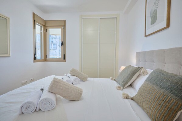 Ein Hotelzimmer mit Bett, Handtüchern, einem Fenster und einer Tür.