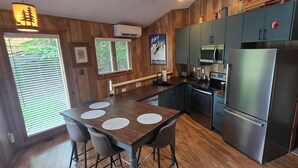 A kitchen with a wooden table, bar stools, a refrigerator, a microwave, and a sink. - New Kitchen! ‖ Hot Tub coming August 7th! ‖ 2 Mins to Slopes ‖ Paved Road Access (Beech Mountain)